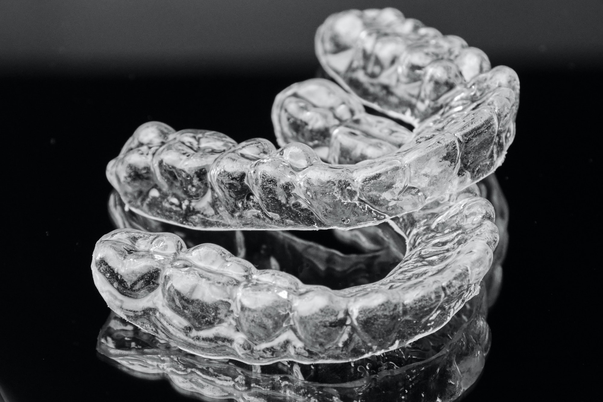 Invisible transparent dental removable braces on the black background. Orthodontic appliance for